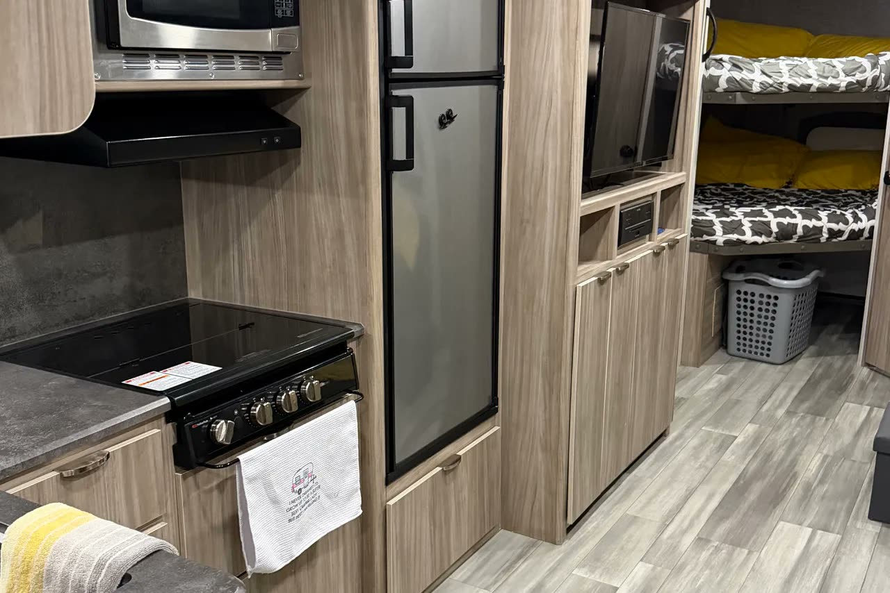 Inside the trailer: the galley with a hob, oven, microwave and fridge, and the bunks beyond with the television between them.